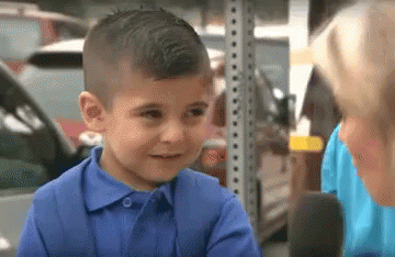 GIF of little boy being asked by a reporter if he's fine and he tries to hold it together but starts balling