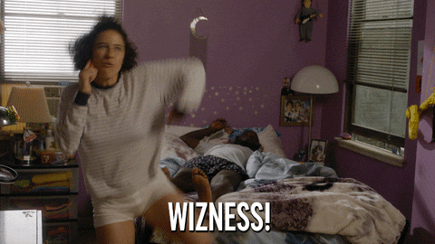 a gif of Ilana Wexler from Broad City kicking her foot into the air while yelling, "Wizness!" into the phone