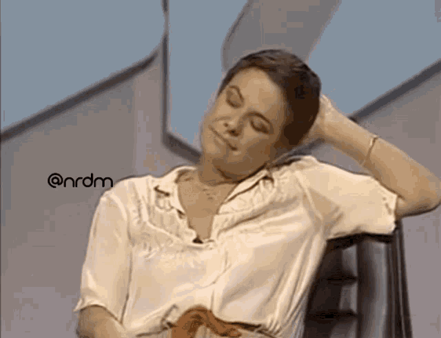 Gif mostra um video de Elis Regina sorridente, sentada numa cadeira giratória, dando tchauzinho com a mão